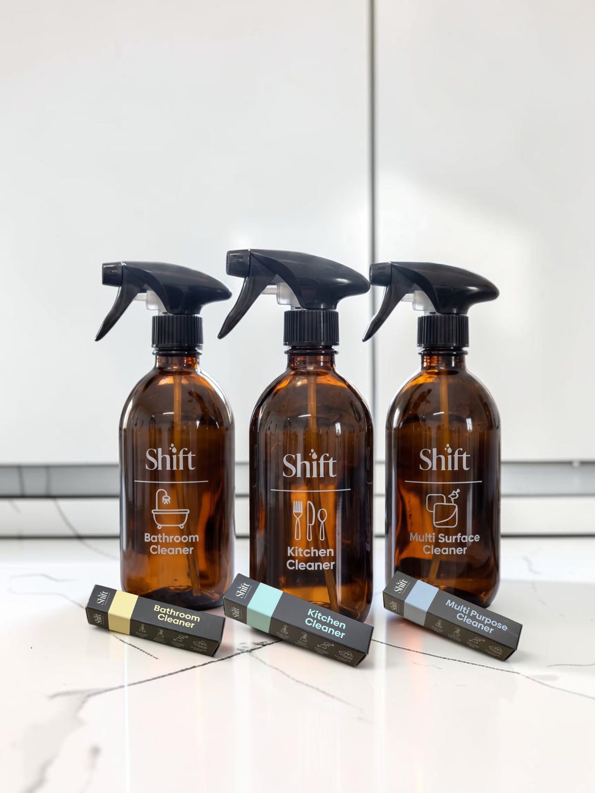 Shift cleaning kit featuring three amber glass spray bottles and matching refill pods for bathroom, kitchen, and surfaces